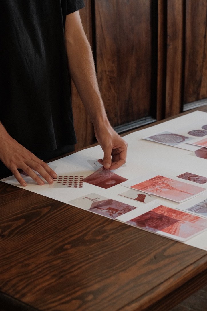 Hands arranging red-toned prints on transparent paper during a collage workshop