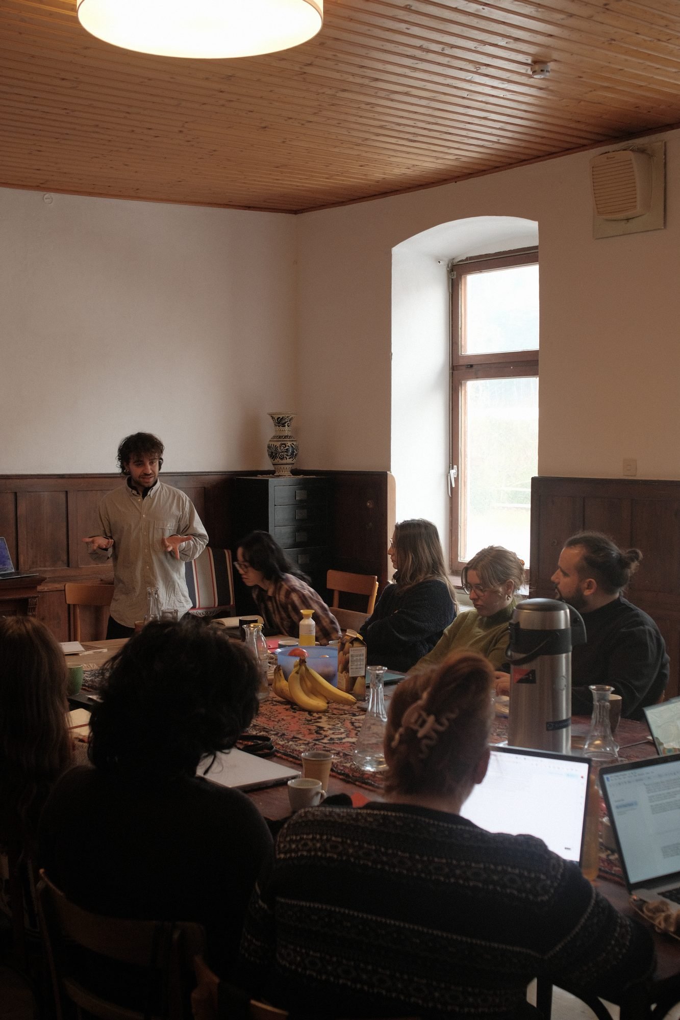 A lecture in a wood-panelled room at Commons Hub, participants listening around a long table