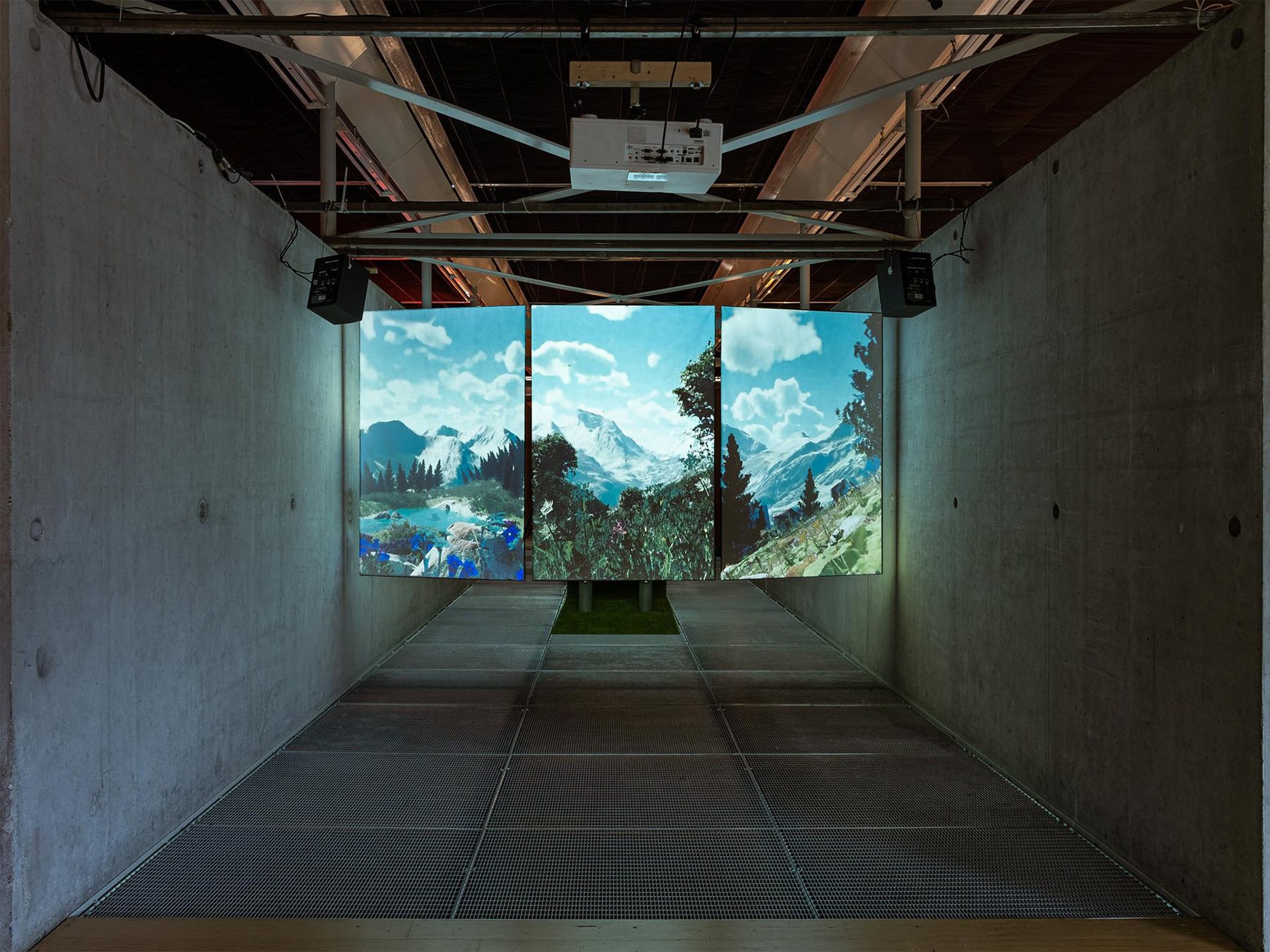 Installation view: a dark concrete hall with a three-panel projection of an alpine landscape at the far end