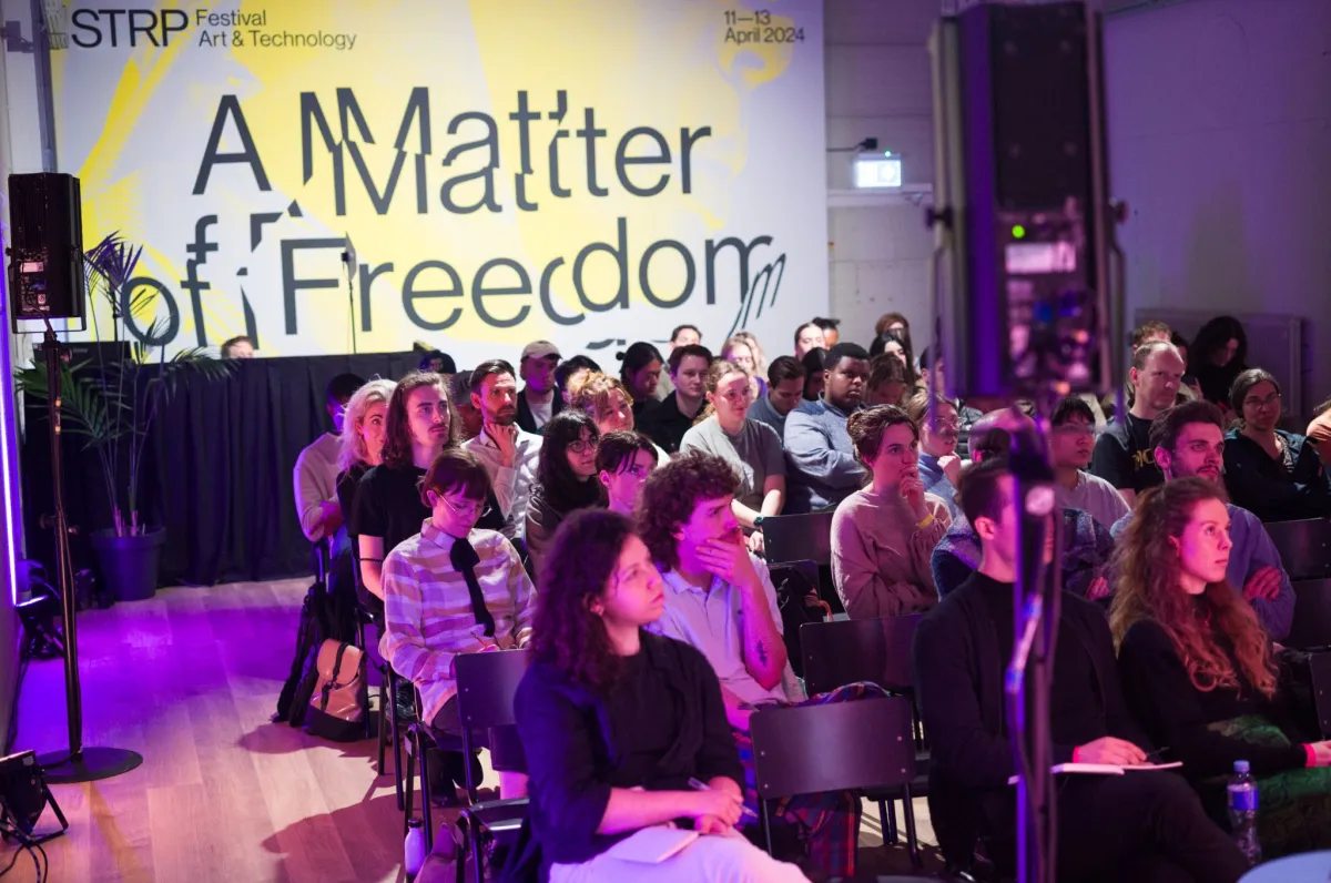 The audience at STRP Festival 2024 in front of a large banner reading A Matter of Freedom, 11–13 April 2024