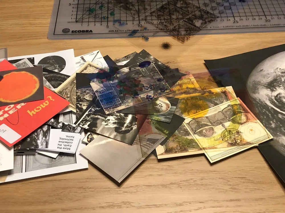 Cut-out prints, transparent sheets and a booklet piled on a wooden table